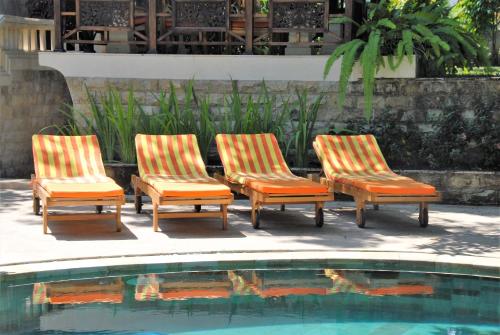 three lounge chairs sitting next to a swimming pool at Jungle Garden Villa in Mayong