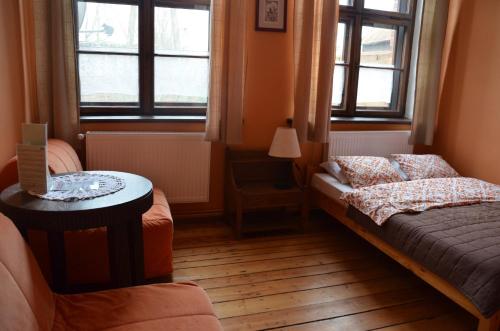 a bedroom with a bed and a table and windows at Stara Szkoła w Harszu in Pozezdrze