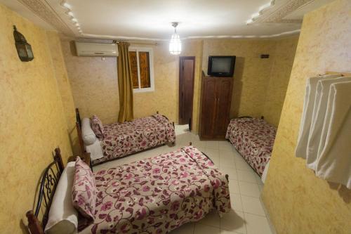 a hotel room with two beds and a tv at Hotel Bab Boujloud in Fès