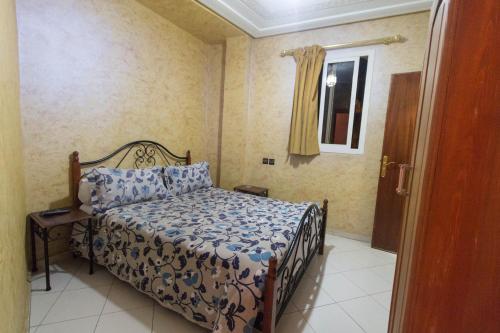 a bedroom with a bed with a blue comforter and a window at Hotel Bab Boujloud in Fès