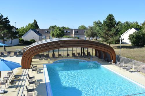 a large swimming pool with chairs and a bridge at Azureva Kerjouanno in Arzon