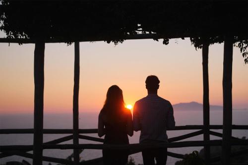 a man and a woman standing in front of a sunset at Hotel Il Girasole in Anacapri
