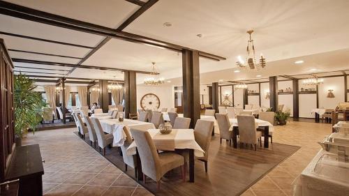 un comedor con mesas blancas y sillas blancas en Hotel Regina, en Sinaia