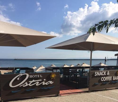 a restaurant with tables and umbrellas on the beach at Hotel Ostria in Kalamata