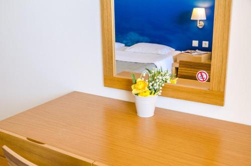 a table with a mirror and a vase with flowers on it at Hotel Nereides in Patitiri