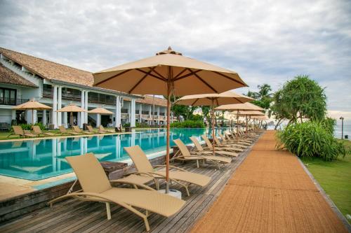 a row of chairs and umbrellas next to a swimming pool at The Fortress Resort & Spa in Koggala