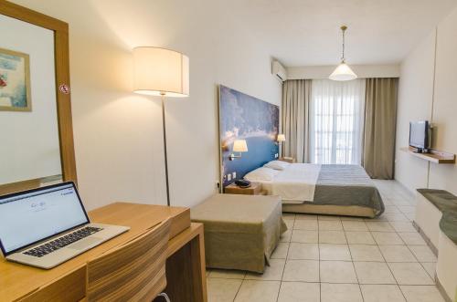 a hotel room with a bed and a laptop on a desk at Hotel Nereides in Patitiri