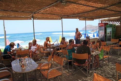 a group of people sitting at tables on the beach at Vaso Apartments in Platanias
