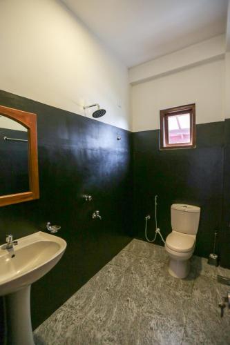 a bathroom with a white toilet and a sink at Lazies Midigama in Midigama