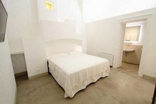a white bedroom with a bed and a sink at Relais Palazzo Zaccaria in Matino