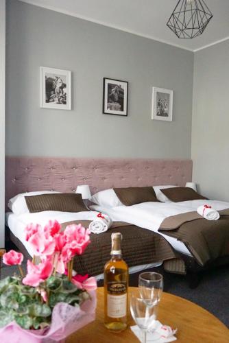 two beds in a room with a table with a bottle of wine at Expolis Residence - City Center MTP TARGI- Reception 24h in Poznań