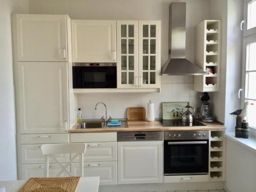 a white kitchen with white cabinets and a sink at MÖWE in Ribnitz-Damgarten