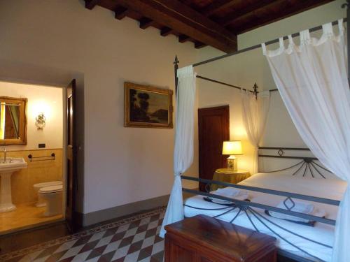 a bedroom with a canopy bed and a bathroom at Villa Eugenia Tuscany with private Pool, Sauna & Gym in Vicchio