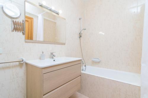 a bathroom with a sink and a tub and a mirror at Can Miquel (Can Picafort) in Can Picafort
