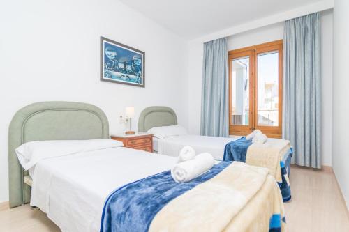 a hotel room with two beds and a window at Can Miquel (Can Picafort) in Can Picafort