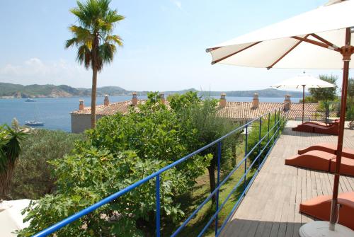 a deck with chairs and an umbrella and the ocean at Hotel Petit Cala Fornells in Paguera