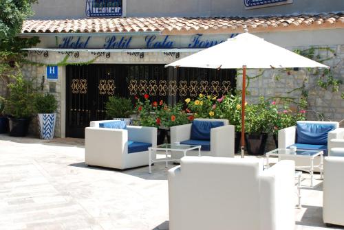 a patio with white chairs and an umbrella at Hotel Petit Cala Fornells in Paguera