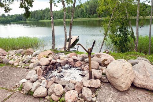 a rock fire pit next to a body of water at Järveoru in Aidaku