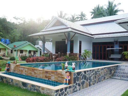 a house with a swimming pool in front of a house at Tara Resort in Nathon