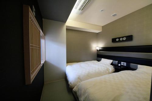 a hotel room with two beds and a window at DogoYaya in Matsuyama
