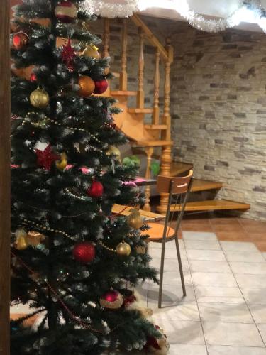 a christmas tree in a room with a chair at Karpatska Mria in Yaremche