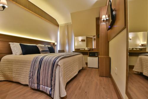 a hotel room with a large bed and a kitchen at Hotel Due Nobili in Gramado