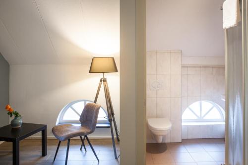 een kamer met een stoel, een toilet en een lamp bij Mert 5 in Beesel