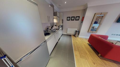 a kitchen with a refrigerator and a red couch at Harrogate Lifestyle Luxury Serviced ApartHotel in Harrogate