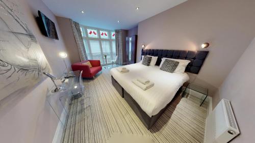 a small bedroom with a bed and a red chair at Harrogate Lifestyle Luxury Serviced ApartHotel in Harrogate