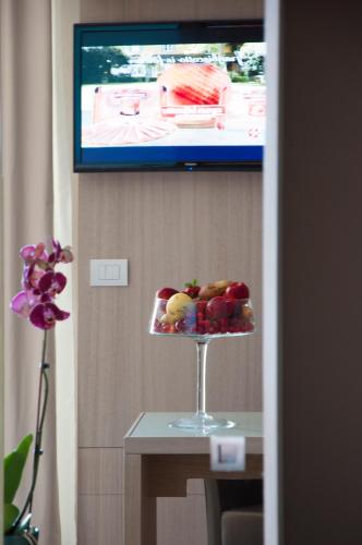 a plate of fruit on a table in front of a tv at Alma di Alghero Hotel in Alghero