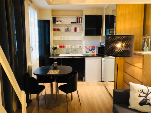 une petite cuisine avec une table et des chaises dans une pièce dans l'établissement Le Petit Neptune, à Versailles