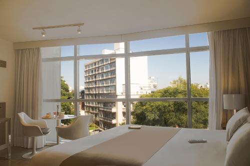 a bedroom with a large bed and a large window at Vivaldi Hotel Loft Punta Carretas in Montevideo