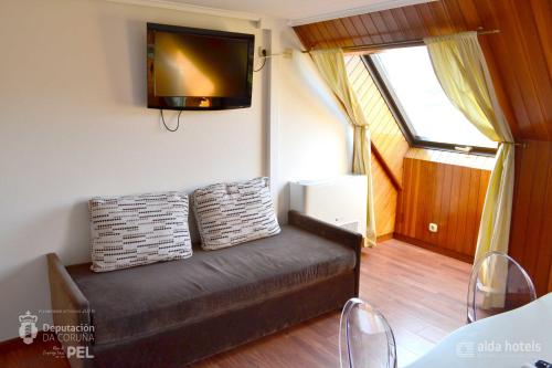 a living room with a couch and a tv on the wall at Hotel Alda Santa Cristina in Perillo