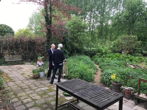 two men walking through a garden with a bench at B&B De Henehoeve in Heks