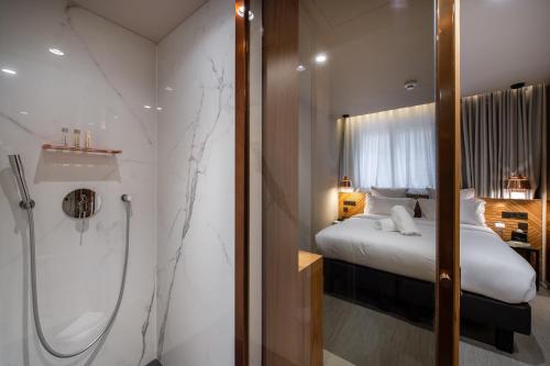 a bathroom with a shower and a bed in a room at 9Hotel Paquis in Geneva
