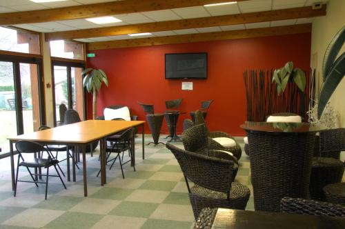 een eetkamer met tafels en stoelen en een tv bij Logis Hôtel Restaurant Chez Nous in Sainte-Croix