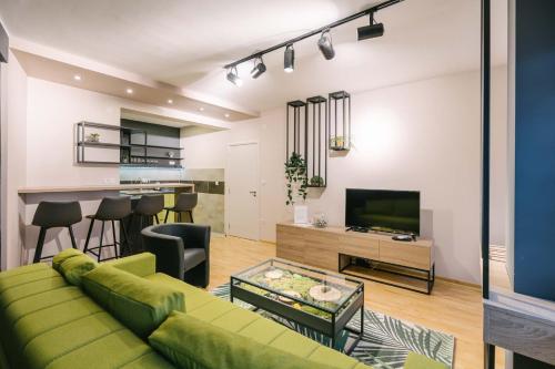 a living room with a green couch and a television at NAR Royalton Accommodation in Niš
