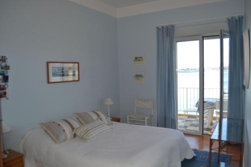 - une chambre blanche avec un lit et un balcon dans l'établissement Flots bleus, à Saint-Jean-de-Luz