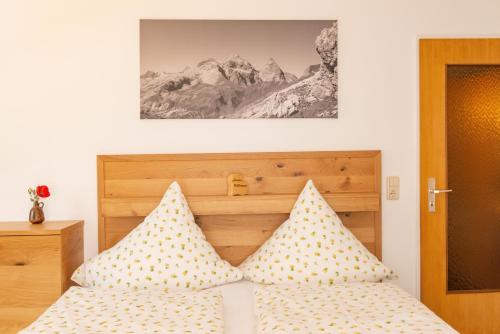 a bedroom with a bed with pillows and a picture on the wall at Gästehaus Schmid in Obermaiselstein