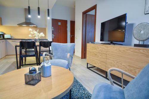 a living room with a tv and a table and chairs at Apartamenty Na Wyspie - Baltic Park - Apartamenty z sypialnią i parkingiem - ul Uzdrowiskowa 24-34 in Świnoujście