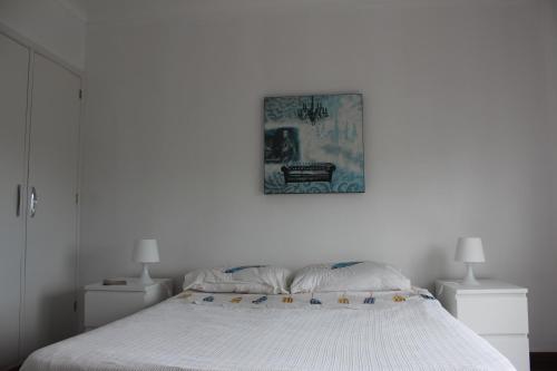 - une chambre blanche avec un lit et une photo sur le mur dans l'établissement Casa da Praceta, à Ponta Delgada