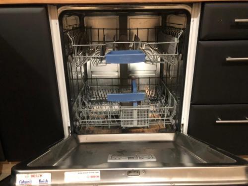 an open dishwasher with dishes inside of it at La Datcha du Parc in Husseren-Wesserling
