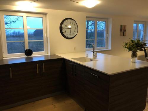 a kitchen with a clock on the wall and a sink at 103 Hvilestedvej in Fredericia