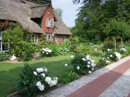 ein Haus mit einem Garten mit weißen Blumen in der Unterkunft Nordsee-Paradies in Barlt