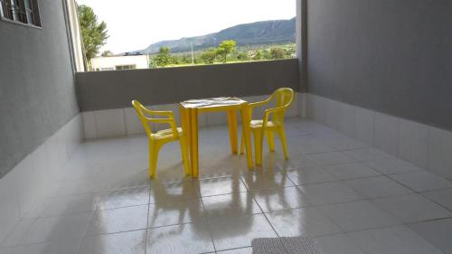a yellow table and two chairs on a balcony at Pousada Agua Quente in Rio Quente