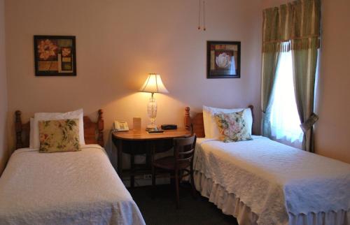 Cette chambre comprend deux lits et une table avec une lampe. dans l'établissement The Inn On Third, à St Petersburg