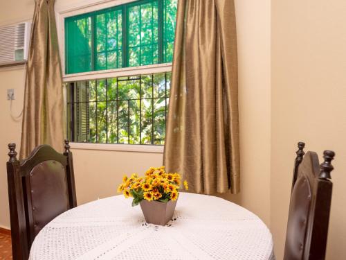 a table with a vase with yellow flowers on it at Hotel Saveiros in Ubatuba