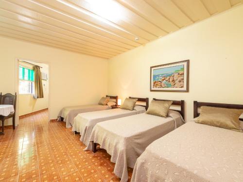 
a hotel room with two beds and a television at Hotel Saveiros in Ubatuba
