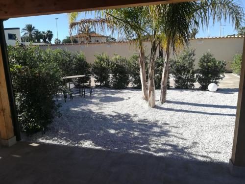 a patio with palm trees and a table and chairs at B&b A Due Passi Dal Sole in Porto Empedocle