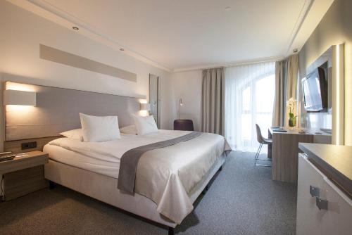 a hotel room with a large bed and a desk at Hotel Erzgiesserei Europe in Munich